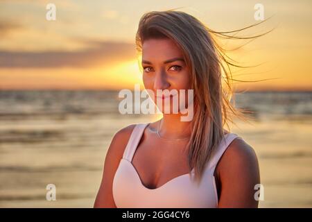 Giovane donna si erge sulla costa durante il tramonto in estate. Foto Stock