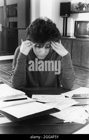 Austin Texas USA, circa 1991: Donna di 35 anni mostra frustrazione mentre cerca di bilanciare il libretto di assegni. ©Bob Daemmrich Foto Stock