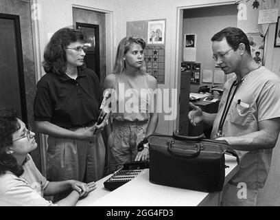Austin Texas USA, circa 1995: Medico che discute come impedire i freddi con il personale al centro privato di cura di giorno. ©Bob Daemmrich Foto Stock