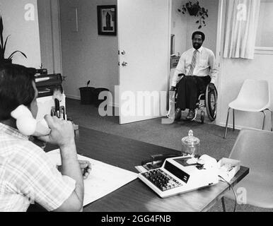 Austin Texas USA, circa 1988: Handicap uomo nero in sedia a rotelle entra in un ufficio per un colloquio di lavoro. ©Bob Daemmrich Foto Stock