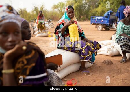 Sacchi e sacchetti di cibo e grano e bottiglie di olio da cucina sono distribuiti a donne e uomini colpiti dal conflitto in Burkina Faso, Africa occidentale. Foto Stock