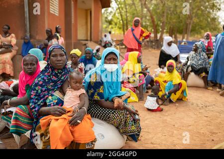 Sacchi e sacchetti di cibo e grano e bottiglie di olio da cucina sono distribuiti a donne e uomini colpiti dal conflitto in Burkina Faso, Africa occidentale. Foto Stock