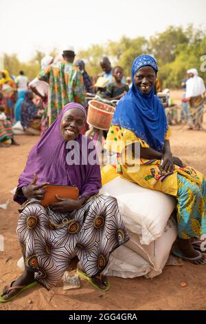 Sacchi e sacchetti di cibo e grano e bottiglie di olio da cucina sono distribuiti a donne e uomini colpiti dal conflitto in Burkina Faso, Africa occidentale. Foto Stock