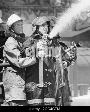 College Station Texas USA, 1978: Vigili del fuoco che indossano attrezzatura da affluenza puntando le manichette alle fiamme alla scuola di addestramento antincendio. ©Bob Daemmrich Foto Stock