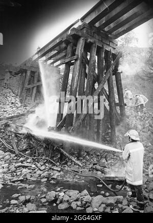 Intorno al 1984, i vigili del fuoco versano l'acqua sotto il ponte dei cavalletti. ©Bob Daemmrich Foto Stock