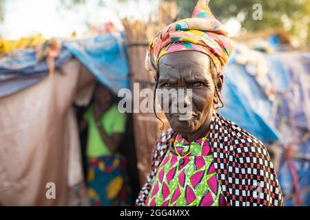 Il Senou Camp si trova al confine meridionale di Bamako, la capitale del Mali. Si tratta di uno degli otto campi informali della città e, di per sé, ospita 223 famiglie e poco più di 1.000 sfollati interni. Le famiglie che vivono qui sono fuggite dalla violenza e dall'insurrezione nella parte settentrionale e centrale del paese. Poiché la maggior parte di loro non ha mezzi di reddito o una normale fonte di cibo, la fame è una sfida quotidiana e la malnutrizione tra la sua popolazione continua ad essere diffusa. Qui, Fatima Barry si trova al di fuori del rifugio improvvisato della sua famiglia. Foto Stock