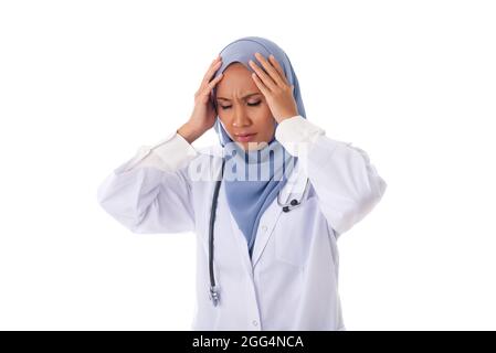 Triste ha sottolineato giovane asiatico musulmana medico in hijab che ha mal di testa su sfondo bianco Foto Stock