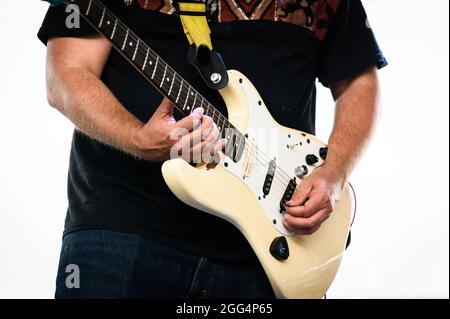 Un musicista suona il collo su una chitarra elettrica bianca mano sinistra Fender Stratocaster. Foto Stock