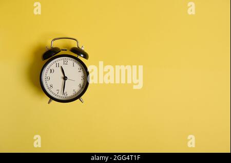 Back to School and Teachers Day Concepts, Business, Organization, Time Management. Sveglia vintage nera su sfondo giallo con spazio per la copia su A. Foto Stock