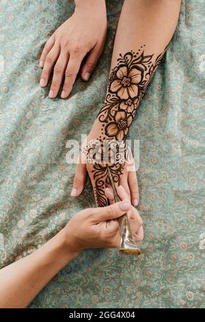 Top view art henné tatuaggio su mani femminili. Master artista che disegna mehndi arabo per sposa prima del matrimonio. Primo piano, vista dall'alto. Design floreale. Cono Foto Stock