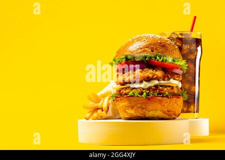 Delizioso hamburger con cola e patatine fritte su sfondo giallo Foto Stock