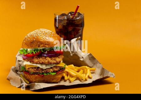 Hamburger di pollo con cola e patatine fritte su sfondo arancione Foto Stock