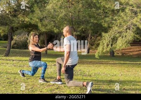 Fitness coppia esercitandosi tenendo le mani nel parco Foto Stock