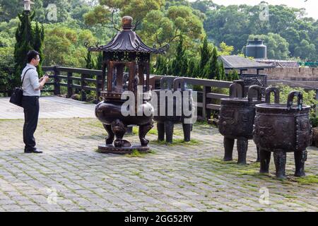 Adoratori che bruciano bastoni incensi al tempio buddista Guan Dao Guan Ying Foto Stock