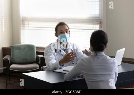 Focalizzato il giovane medico africano americano e paziente indiano parlare. Foto Stock