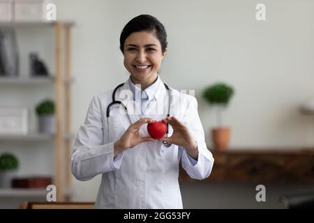 Buon medico indiano sicuro che tiene la figura di cuore nelle mani. Foto Stock