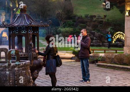 Adoratori che bruciano bastoni incensi al tempio buddista Guan Dao Guan Ying Foto Stock