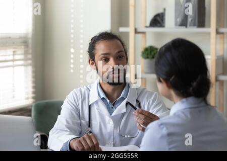 Concentrato giovane medico afroamericano consulenza indiano paziente. Foto Stock
