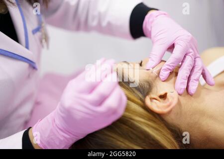 Medico iniettando i fili di trattamento di sutura di PDO nella faccia di una donna. Foto Stock