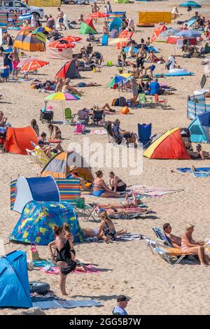 Il caldo intenso e il sole senza sosta attirano la folla di turisti sulla Fistral Beach a Newquay in Cornovaglia. Foto Stock