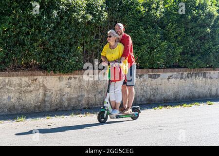 ROMA ITALIA, REGNO UNITO. 29 agosto 2021. Un uomo e una donna che cavalcano insieme a Villa Borghese su uno scooter elettrico Lime in una giornata calda a Roma. Gli scooter elettrici sono diventati popolari nella capitale romana e vengono utilizzati regolarmente come mezzi di trasporto per la mobilità. Credit: amer Ghazzal/Alamy Live News Foto Stock