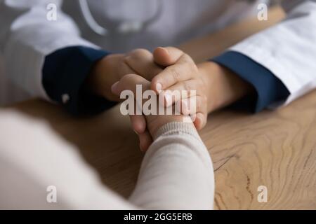 Primo piano gentile medico che tiene la mano o paziente anziano. Foto Stock