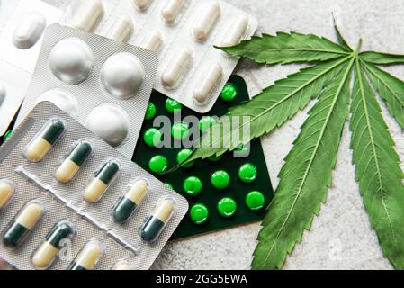 Pillole CBD. Gruppo di capsule trasparenti di Cannabidiolo CBD e foglia di canapa su fondo di cemento Foto Stock