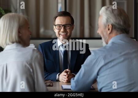 Sorridente manager uomo d'affari in occhiali consulenza coppia matura in riunione Foto Stock