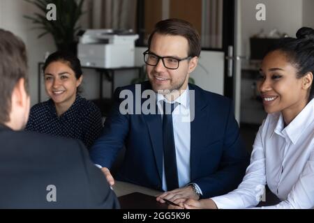 Primo piano sorridente uomo d'affari fiducioso che agita la mano del partner alla riunione Foto Stock