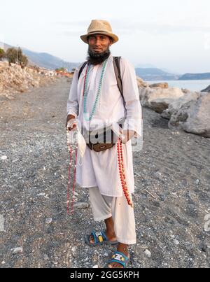 Peddler immigrato dal Bangladesh sulla spiaggia, vendendo collana fatta a mano in Italia Foto Stock