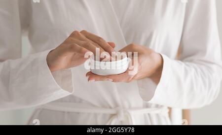 Primo piano giovane donna che tiene crema idratante nelle mani. Foto Stock