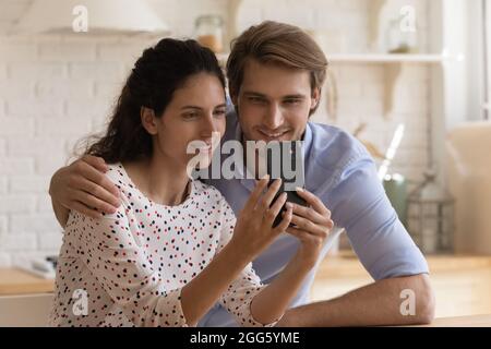 Sorridente coppia di famiglia utilizzando le applicazioni per smartphone. Foto Stock