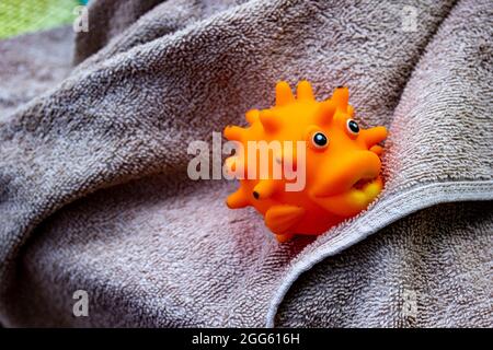 Primo piano di un giocattolo arancione in plastica su un asciugamano grigio Foto Stock