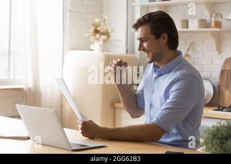 Giovane gioioso che celebra il successo leggendo le notizie in lettera. Foto Stock