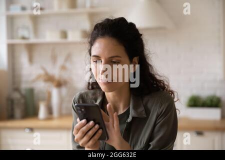 Giovane bella ispanica donna utilizzando l'applicazione smartphone. Foto Stock