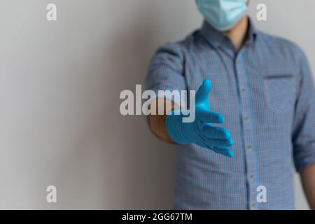 Uomo che indossa maschera medica viso e guanti in lattice di gomma blu Foto Stock