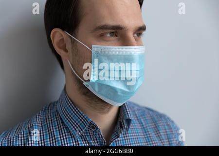 Primo piano di uomo millenario con maschera medica blu pallido Foto Stock