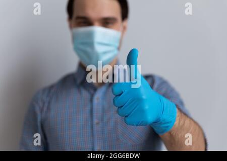Ragazzo positivo millenario in maschera medica e guanti in lattice Foto Stock
