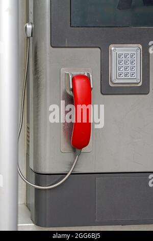 Maniglia rossa sul telefono pubblico con tastierino numerico Foto Stock