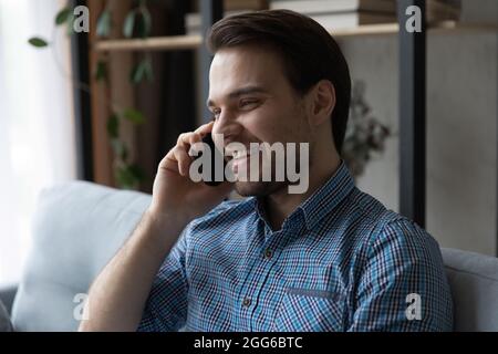 Ragazzo felice millenario godendo piacevole conversazione telefonica Foto Stock