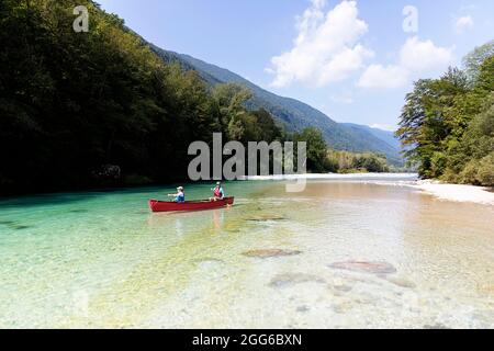 Madre e figlio che remano in una canoa rossa sul fiume Soca vicino a Tolmin, Slovenia Foto Stock