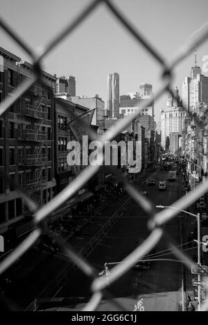 Manhattan, New York, USA, Febbraio 2019: Vista attraverso una recinzione a Chinatown nella città di New York. Paesaggio urbano strada skyline grattacieli Foto Stock