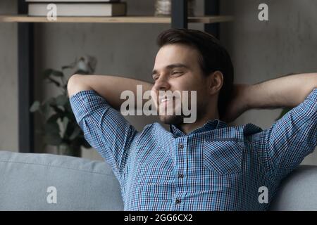 Un ragazzo felice e premuroso che si rilassa sul divano di casa Foto Stock