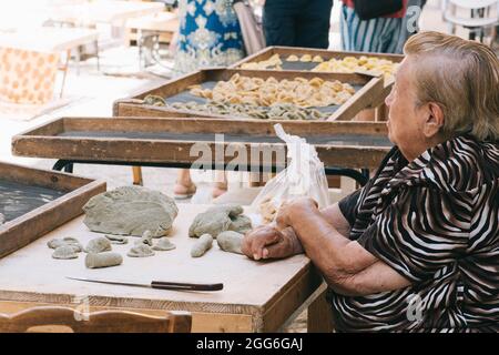 Donna anziana locale che vende per le strade della città vecchia di Bari orecchiette o orecchietta, fatta con grano duro e acqua, pasta fatta a mano della Puglia Foto Stock