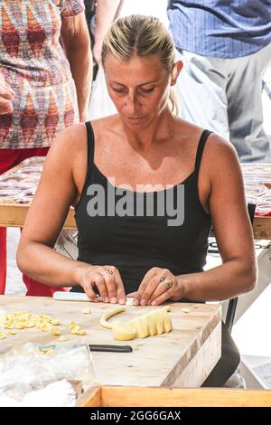 Bella donna locale che si prepara nella strada del centro storico di Bari orecchiette fresche o orecchietta, fatta con grano duro e acqua, pasta fatta a mano Foto Stock