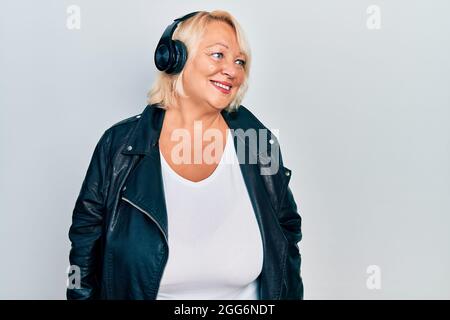 Donna bionda del Medio Evo che ascolta musica con cuffie che guardano da vicino con sorriso sul viso, espressione naturale. Ridendo sicuro. Foto Stock