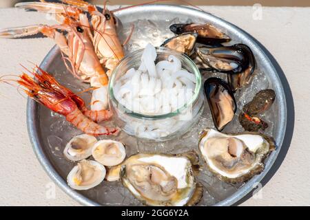 Piatto di frutti di mare freschi e crudi o di alimenti pronti a mangiare con gamberi, gamberetti, ostriche, cozze, conchiglie, seppie, primo piano Foto Stock