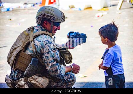 210828-M-JU875-1024 HAMID KARZAI INTERNATIONAL AIRPORT, Afghanistan (28 agosto 2021) UN Marine assegnato alla Joint Task Force-Crisis Response mostra a un bambino una fotografia all'aeroporto internazionale Hamid Karzai, Afghanistan, 28 agosto. I membri del servizio degli Stati Uniti stanno assistendo il Dipartimento di Stato con un'operazione DI evacuazione non combattente (NEO) in Afghanistan. (STATI UNITI Foto del corpo marino di CPL. Davis Harris) Foto Stock