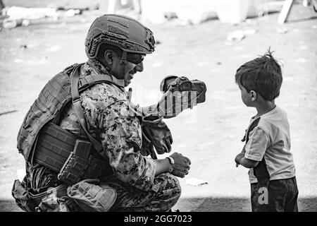 210828-M-JU875-1024 HAMID KARZAI INTERNATIONAL AIRPORT, Afghanistan (28 agosto 2021) UN Marine assegnato alla Joint Task Force-Crisis Response mostra a un bambino una fotografia all'aeroporto internazionale Hamid Karzai, Afghanistan, 28 agosto. I membri del servizio degli Stati Uniti stanno assistendo il Dipartimento di Stato con un'operazione DI evacuazione non combattente (NEO) in Afghanistan. (STATI UNITI Foto del corpo marino di CPL. Davis Harris) Foto Stock