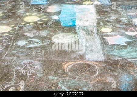 Disegno in gesso sull'asfalto. I bambini dipinse l'asfalto con pastelli. Un semplice sfondo di disegni fatti dagli scolari. Foto Stock